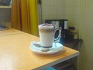 A caffe mocha sitting on a white plate and beige table.