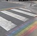 Zebra crossing with rainbow stripes running perpendiculary along its sides.