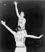 A basketball player, wearing a jersey with a word "PRINCETON" and the number "42", is jumping in front of another basketball player who is wearing a jersey with the number "24".