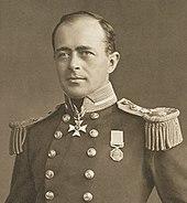 Man with receding hairline, looking left, wearing naval uniform with medals, polished buttons and heavy shoulder decorations