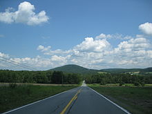 View of a long paved road and a mountain in the distance.