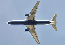 Underside view of a jet in-flight. Each wing of the two wings have an engine. Towards the left are the horizontal stabilizers.