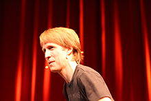 A blond man wearing a short black shirt