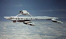 An airborne structure resembling a seagoing aircraft carrier, hovering at high altitude above clouds