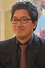 A middle-aged Japanese man with glasses, a black suit, and a red tie.