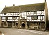 White fronted building with black beams prominent. Over the door is a sign saying The George Inn, Wadworths.