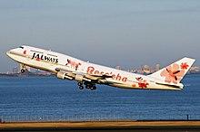 An aircraft taking off from the runway, with a city skyline on the background