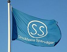 A flag of Strockholms Spårvägar's logo and wordmark, at the top of a flagpole