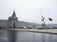 wall of building with text that says Attica Correctional Facility. Flags are visible outside at half-staff.