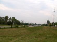A rural highway with a wide right-of-way vanishes into the distance.