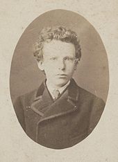Black-and-white formal head shot photo of the artist as a boy in jacket and tie. He has thick curly hair and very pale-coloured eyes with a wary, uneasy expression.