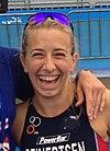 Sarah Reinersten wearing blue-tinted sunglasses on top of her head and smiling widely