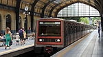 Square grey-and-red train pulling into a station