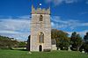 Square stone tower surrounded by trees and grass.