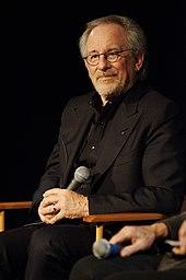 Steven Spielberg sits on a chair with a microphone in his hand