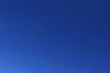 A section of blue sky, featureless other than some light in the lower left corner