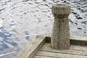 bitt - a strong post (as on a wharf or quay or ship for attaching mooring lines)